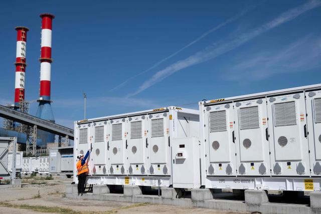 This photograph taken on September 18, 2026, shows a worker checking a battery container in the Contur Global's 500 MWh battery energy storage system near the Maritsa East 3 TPP near Galabovo. As Eastern Europe's power sector has taken a hit from a record drought, Bulgaria has benefitted from a surge in solar-powered battery projects across the country. Around a hundred large battery energy storage system (BESS) sites are now operating, most of them built in the past two years. (Photo by Nikolay DOYCHINOV / AFP)