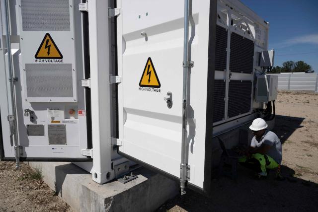 This photograph taken on September 18, 2026, shows workers checking battery containers in the Suntera Re's 450 MWh battery energy storage facility near the village of Pyasachevo. As Eastern Europe's power sector has taken a hit from a record drought, Bulgaria has benefitted from a surge in solar-powered battery projects across the country. Around a hundred large battery energy storage system (BESS) sites are now operating, most of them built in the past two years. (Photo by Nikolay DOYCHINOV / AFP)