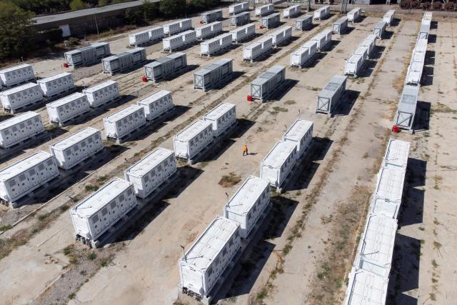 This aerial photograph taken on September 18, 2026, shows a worker walking in the Contur Global's 500 MWh battery energy storage system near the Maritsa East 3 TPP near Galabovo. As Eastern Europe's power sector has taken a hit from a record drought, Bulgaria has benefitted from a surge in solar-powered battery projects across the country. Around a hundred large battery energy storage system (BESS) sites are now operating, most of them built in the past two years. (Photo by Nikolay DOYCHINOV / AFP)