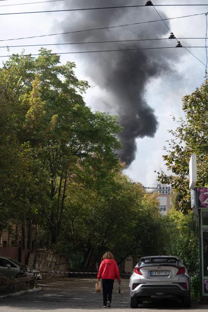 A woman walks along a street as smoke rises from a site of a drone strike in Kyiv on September 23, 2026, amid the Russian invasion of Ukraine. Ukraine on September 23, 2026 accused Russia of increasing its targeting of civilian transport infrastructure after renewed attacks on petrol stations, shipping and railways left at least two dead. (Photo by Genya SAVILOV / AFP)