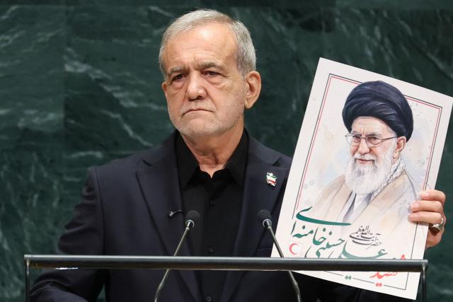 Iran's President Masoud Pezeshkian speaks as he holds a picture of Ali Khamenei, former Supreme Leader of Iran, during the 81st United Nations General Assembly at the United Nations Headquarters in New York, on September 23, 2026. (Photo by TIMOTHY A. CLARY / AFP)