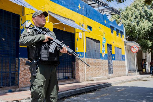 A police officer stands guard on a street following a military operation against the drug-related armed group Conquering Self Defense Forces of the Sierra Nevada (ACSN) in Santa Marta, Colombia on September 23, 2026. Colombia's President Abelardo de la Espriella sent troops into Santa Marta after an armed group attacked shops and burnt vehicles across the Caribbean city, he announced on September 22, 2026. The chaos followed an earlier announcement by the president that authorities had killed 13 members of the self-styled Conquering Self Defense Forces of the Sierra Nevada (ACSN), an armed group which controls cocaine trafficking routes. (Photo by Marco PERDOMO / AFP)