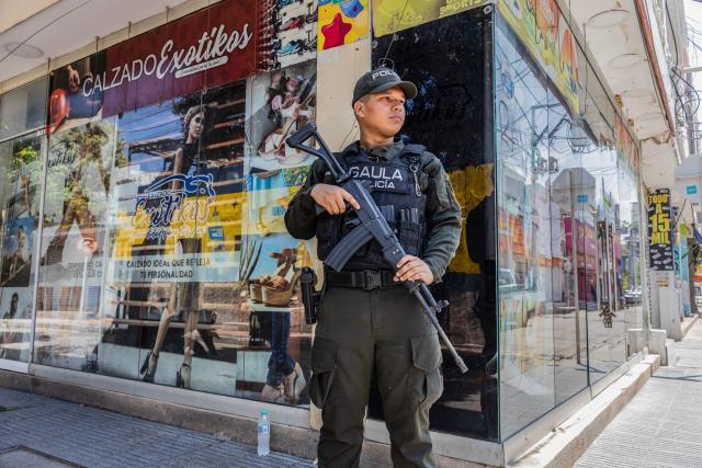 A police officer stands guard on a street following a military operation against the drug-related armed group Conquering Self Defense Forces of the Sierra Nevada (ACSN) in Santa Marta, Colombia on September 23, 2026. Colombia's President Abelardo de la Espriella sent troops into Santa Marta after an armed group attacked shops and burnt vehicles across the Caribbean city, he announced on September 22, 2026. The chaos followed an earlier announcement by the president that authorities had killed 13 members of the self-styled Conquering Self Defense Forces of the Sierra Nevada (ACSN), an armed group which controls cocaine trafficking routes. (Photo by Marco PERDOMO / AFP)