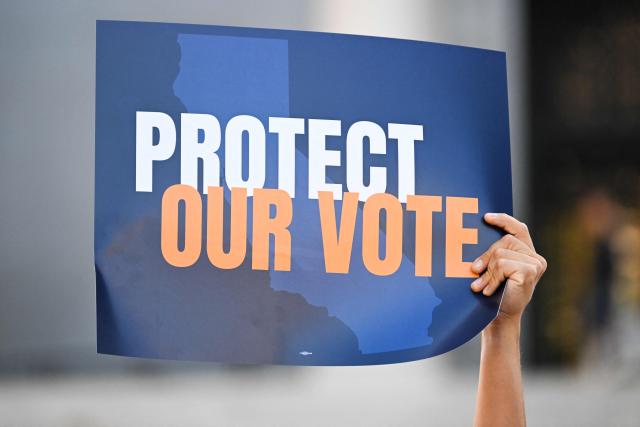 A person holds a sign reading “Protect Our Vote” during a news conference about protecting voting rights ahead the November midterm elections, in Los Angeles, California on September 23, 2026. (Photo by Patrick T. Fallon / AFP)
