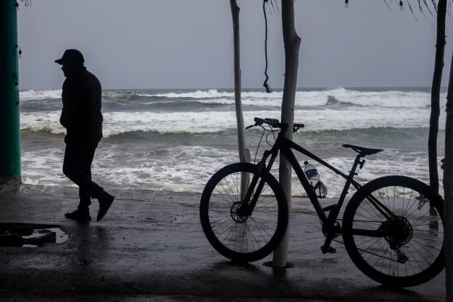 A man walks along the shore as strong waves churn the waters off Playa Azul, in the municipality of Lazaro Cardenas, Michoacan, Mexico, on September 23, 2026. Hurricane Polo strengthened to the highest category on September 22 in the Mexican Pacific, with no forecast of making landfall but with heavy rainfall expected. Polo intensified from Category 1 to Category 5 on the Saffir-Simpson scale in less than 24 hours. (Photo by Enrique Castro / AFP)