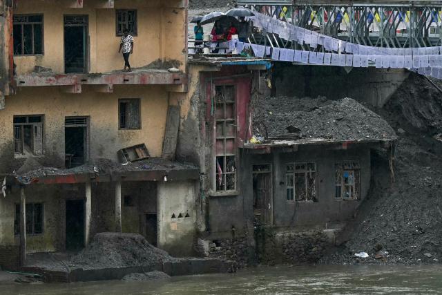 People are seen near a bridge over the Tadi river, rebuilt by army personnel after it was damaged during the August 26 flash flood, at Devighat in Nepal's Nuwakot district on September 24, 2026. The catastrophic August 26 flood was triggered by a Himalayan glacial mountain collapse on the China-Nepal border, that scientists have linked to climate change. The tsunmai-like floodwaters tore through mountain districts, destroying roads, bridges and hydropower dams, and killed at least 1,446 people. (Photo by PRAKASH MATHEMA / AFP)