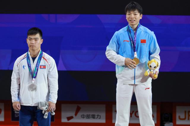 China's Yang Yang (R) celebrates with his gold medal, next to North Korea's Pang Un Chol who won the silver medal, after the men's 60kg weightlifting final at the 2026 Asian Games in Nagoya on September 24, 2026. (Photo by DAVID GRAY / AFP)