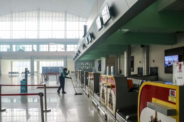 An airport worker cleans the check-in area at an empty Tjilik Riwut Airport terminal in Palangkaraya, Central Kalimantan, on September 24, 2026. Low visibility caused by persistent forest fires has hampered both commercial air travel and aerial firefighting operations across the province. (Photo by REINA / AFP)