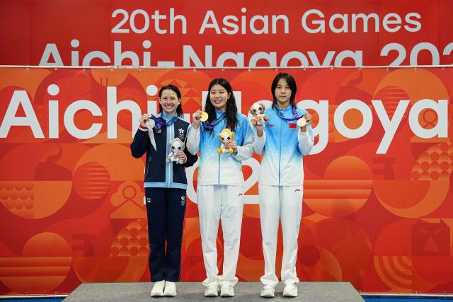 Silver medallist Hong Kong's Siobhan Bernadette Haughey (L), gold medallist China's Wu Qingfeng (C) and bronze medallist China's Cheng Yujie (R) celebrate on the podium during the victory ceremony of the women's 50m freestyle swimming event during the 2026 Asian Games at the Tokyo Aquatics Centre in Tokyo on September 24, 2026. (Photo by Yuichi YAMAZAKI / AFP)