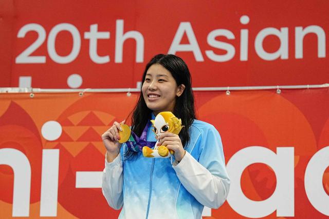 Gold medallist China's Wu Qingfeng celebrates on the podium during the victory ceremony of the women's 50m freestyle swimming event during the 2026 Asian Games at the Tokyo Aquatics Centre in Tokyo on September 24, 2026. (Photo by Yuichi YAMAZAKI / AFP)