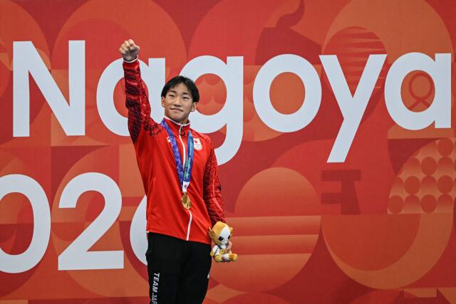 Gold medallist and world record holder Japan's Shin Ohashi celebrates on the podium during the victory ceremony of the men's 200m breaststroke swimming event during the 2026 Asian Games at the Tokyo Aquatics Centre in Tokyo on September 24, 2026. (Photo by ANDREW CABALLERO-REYNOLDS / AFP)