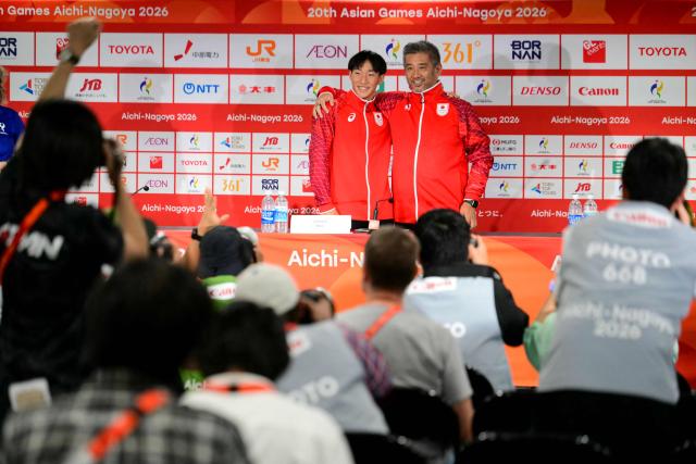 Gold medallist and world record holder Japan's Shin Ohashi (CL) and his coach Shin Ota (CR) pose for a photograpg during a press conference following the victory ceremony of the men's 200m breaststroke swimming event during the 2026 Asian Games at the Tokyo Aquatics Centre in Tokyo on September 24, 2026. (Photo by Yuichi YAMAZAKI / AFP)