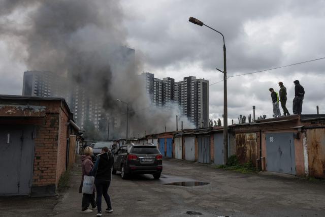 Local residents watch smoke rising above garages following an air attack in Kyiv on September 24, 2026, amid the Russian invasion of Ukraine. A barrage of Russian drone and missile strikes pummelled Ukraine on September 24, killing six agricultural workers in the east alongside two in the capital, Kyiv, in the latest in an intensifying exchange of attacks. (Photo by Vladyslav Musiienko / AFP)