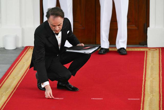 A White House aide places position markers for US President Donald Trump, First Lady Melania Trump, Chinese President Xi Jinping and his wife Peng Liyuan ahead of a photo opportunity on the North Portico steps before a state dinner at the White House in Washington, DC, on September 24, 2026. President Xi is on a State visit to the United States from September 23 to 25. (Photo by SAUL LOEB / AFP)