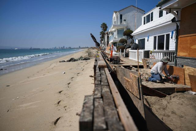 A worker repairs a home along the boardwalk that was damaged by previous storms as residents prepare for elevated surf, coastal flooding and beach erosion ahead of Hurricane Polo in Long Beach, California, on September 24, 2026. On September 21, California's governor declared a state of emergency as the US west coast readies for what is expected to be a damaging El Nino. Forecasters say the coming months could bring powerful and damaging storms to the region because of this weather pattern, with the threat of higher-than-usual tides that could trigger coastal flooding. (Photo by Patrick T. Fallon / AFP)