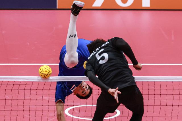 Thailand's Phutawan Sopa (L) kicks the ball past Malaysia's Mohamad Azlan Alias (R) during the men's team regu sepak takraw gold medal match between Thailand and Malaysia at Nagoya City Mizuho Park Gymnasium in Nagoya on September 25, 2026. (Photo by DAVID GRAY / AFP)