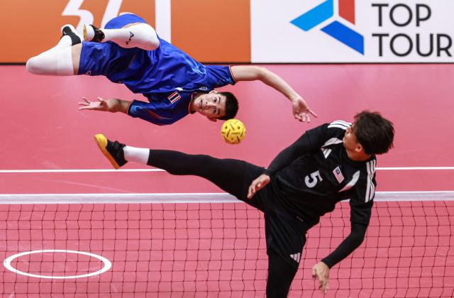 TOPSHOT - Thailand's Phutawan Sopa (L) kicks the ball past Malaysia's Mohamad Azlan Alias (R) during the men's team regu sepak takraw gold medal match between Thailand and Malaysia at Nagoya City Mizuho Park Gymnasium in Nagoya on September 25, 2026. (Photo by DAVID GRAY / AFP)