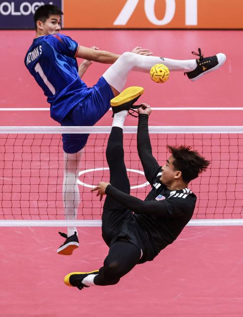 Malaysia's Mohamad Azlan Alias (R) kicks the ball as Thailand's Phutawan Sopa (L) attempts to block during the men's team regu sepak takraw gold medal match between Thailand and Malaysia at Nagoya City Mizuho Park Gymnasium in Nagoya on September 25, 2026. (Photo by DAVID GRAY / AFP)