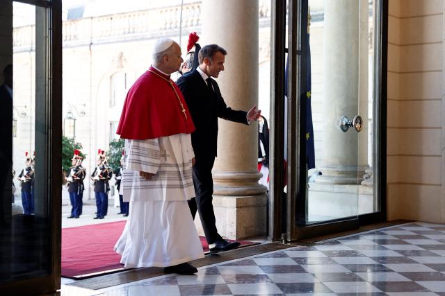 France's President Emmanuel Macron (R) welcomes Pope Leo XIV (L) ahead of a meeting at the Elysee Presidential Palace, in Paris on September 25, 2026 at the start of his four days visit to France. Pope Leo XIV begins an official visit to France on September 25, with several thorny issues hanging over the trip, from clerical sexual abuse to the country's new assisted dying law. (Photo by Benoit Tessier / POOL / AFP)