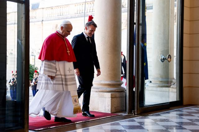 France's President Emmanuel Macron (R) welcomes Pope Leo XIV (L) ahead of a meeting at the Elysee Presidential Palace, in Paris on September 25, 2026 at the start of his four days visit to France. Pope Leo XIV begins an official visit to France on September 25, with several thorny issues hanging over the trip, from clerical sexual abuse to the country's new assisted dying law. (Photo by Benoit Tessier / POOL / AFP)