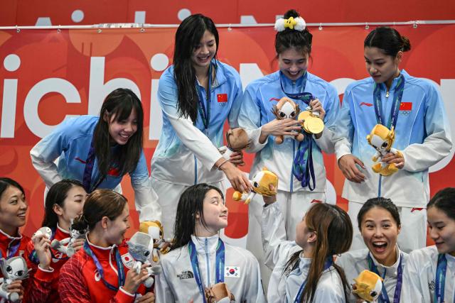 Silver medallists Japan's Rio Shirai, Satomi Suzuki, Rikako Ikee and Nagisa Ikemoto, gold medallists China's Peng Xuwei, Tang Qianting, Zhang Yufei and Yu Yiting, and bronze medallists South Korea's Kim Seung-won, Park Si-eun, An Se-hyeon and Hur Yeon-kyung interact on the podium during the victory ceremony of the women's 4 x 100m medley relay swimming event during the 2026 Asian Games at the Tokyo Aquatics Centre in Tokyo on September 25, 2026. (Photo by ANDREW CABALLERO-REYNOLDS / AFP)