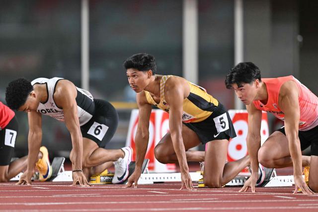 (L-R) South Korea's Joeljin Nwamadi, Malaysia's Muhd Azeem Fahmi and Japan's Yuki Koike take starting stance before the men's 100m semifinal during the 2026 Asian Games at Nagoya City Mizuho Park Athletic Stadium in Nagoya, Aichi Prefecture on September 25, 2026. (Photo by MOHD RASFAN / AFP)