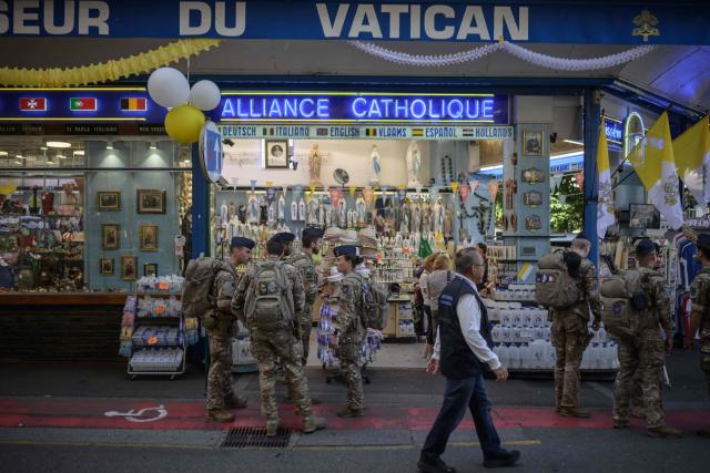 French soldiers stand before a shop selling religious souvenirs in Lourdes, south-western France, a day ahead of the Pope's visit, on September 25, 2026. On the first official papal trip in 18 years to a proudly secular country that has since 1901 separated church and state, Pope Leo will visit Lourdes, a pilgrimage site for Christians worldwide where he will privately meet victims of clerical sex abuse, and Metz, near the German border, where he is to further speak about peace in Europe. (Photo by Ed JONES / AFP)