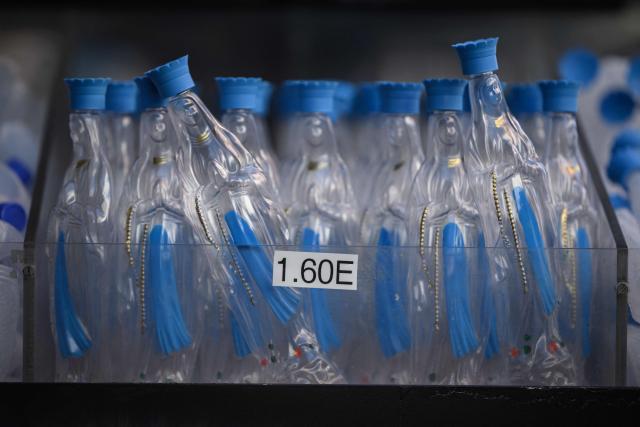 This photographh shows bottle for collecting holy water displayed for sale at a shop in Lourdes, south-western France, a day ahead of the Pope's visit, on September 25, 2026. On the first official papal trip in 18 years to a proudly secular country that has since 1901 separated church and state, Pope Leo will visit Lourdes, a pilgrimage site for Christians worldwide where he will privately meet victims of clerical sex abuse, and Metz, near the German border, where he is to further speak about peace in Europe. (Photo by Ed JONES / AFP)