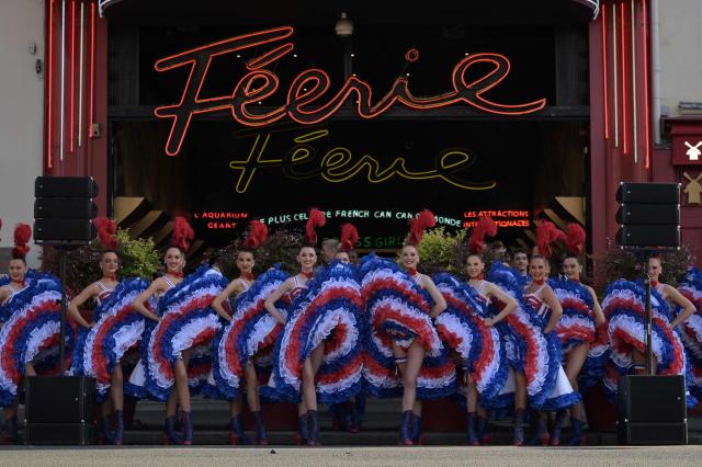 (FILES) Dancers from the Moulin Rouge cabaret perform in the street during the Olympic torch relay in Paris, on July 15, 2024, ahead of the Paris 2024 Olympic and Paralympic Games. With red feathers, sequins, accordions and the French cancan, cabaret shows are set to enjoy a three-month spotlight across France aimed at raising the profile of the rich and diverse art form that has been entertaining audiences for more than a century. The "cabaret season" organised as part of a support plan by the Culture Ministry, was officially launched on September 24, 2026 at Paris's Théâtre de Chaillot. (Photo by Bertrand GUAY / AFP)
