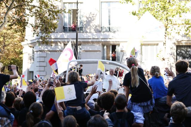 Pope Leo XIV waves to the crowd while riding in the Papamobile (popemobile) through the streets of Paris on September 25, 2026 as part of his four days visit to France. (Photo by Anne-Christine POUJOULAT / AFP)