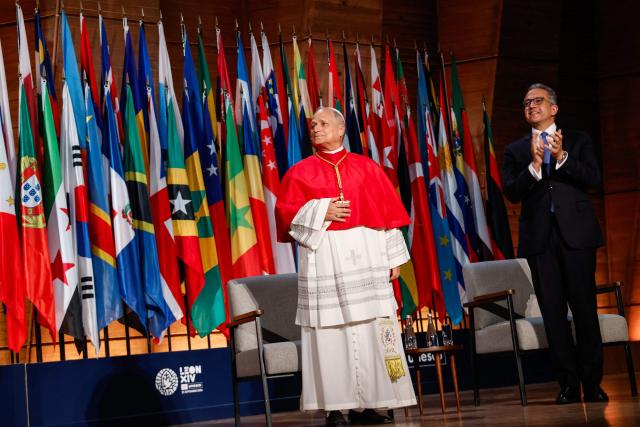 Pope Leo XIV (L) reacts as UNESCO Director-General Khaled El-Enany (R) applauds upon his arrival on stage to deliver a speech at the UNESCO headquarters, in Paris on September 25, 2026 during his four days visit to France. (Photo by Remo Casilli / POOL / AFP)