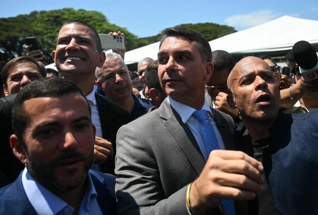 Brazil's senator and presidential candidate for the Liberal Party (PL) Flavio Bolsonaro (C) and state deputy and candidate for governor of Rio de Janeiro state Douglas Ruas (2nd L) leave after a graduation ceremony at the Center of Improvement and Training of Soldiers (CFAP) at Sulacap neighbourhood in Rio de Janeiro, Brazil, on September 25, 2026. Brazil will hold presidential election on October 4, 2026. (Photo by MAURO PIMENTEL / AFP)
