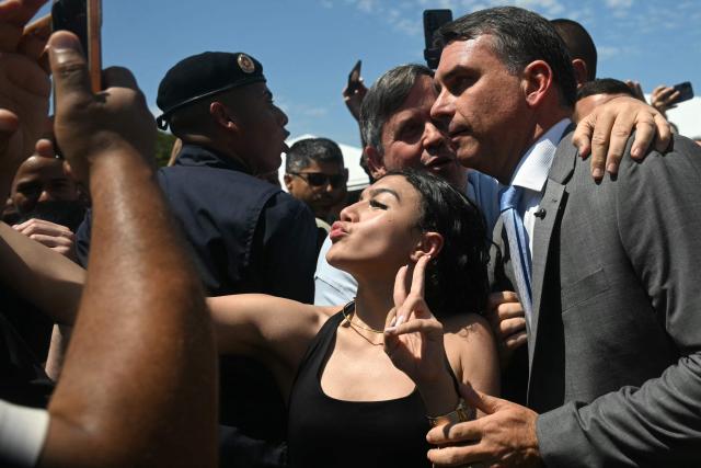 Brazil's senator and presidential candidate for the Liberal Party (PL) Flavio Bolsonaro poses for a selfie with a follower while leaving the Center of Improvement and Training of Soldiers (CFAP) at Sulacap neighbourhood in Rio de Janeiro, Brazil, on September 25, 2026. Brazil will hold presidential election on October 4, 2026. (Photo by MAURO PIMENTEL / AFP)