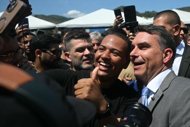 Brazil's senator and presidential candidate for the Liberal Party (PL) Flavio Bolsonaro poses for a selfie with a follower while leaving the Center of Improvement and Training of Soldiers (CFAP) at Sulacap neighbourhood in Rio de Janeiro, Brazil, on September 25, 2026. Brazil will hold presidential election on October 4, 2026. (Photo by MAURO PIMENTEL / AFP)