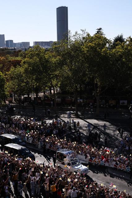 Pope Leo XIV waves to the crowd while riding in the Papamobile (popemobile) on a street, as the Montparnasse tower is seen in the background in Paris on September 25, 2026 as part of his four days visit to France. (Photo by SIMON WOHLFAHRT / AFP)