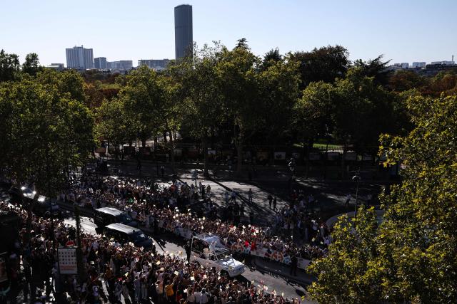 Pope Leo XIV waves to the crowd while riding in the Papamobile (popemobile) on a street, as the Montparnasse tower is seen in the background in Paris on September 25, 2026 as part of his four days visit to France. (Photo by SIMON WOHLFAHRT / AFP)