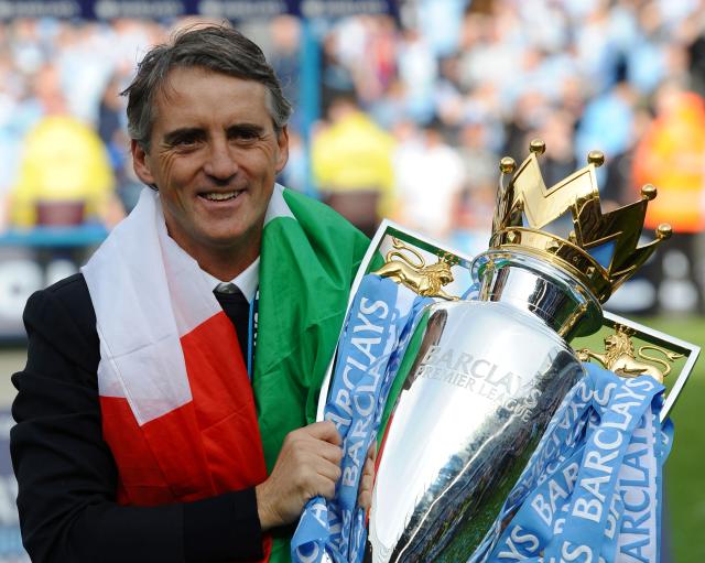 (FILES) Manchester City's Italian manager Roberto Mancini celebrates on the pitch with the Premier League trophy after their 3-2 victory over Queens Park Rangers in the English Premier League football match between Manchester City and Queens Park Rangers at The Etihad stadium in Manchester, north-west England on May 13, 2012. Manchester City won the game 3-2 to secure their first title since 1968. This is the first time that the Premier league title has been decided on goal-difference, Manchester City and Manchester United both finishing on 89 points. Manchester City have been found guilty of all but one of 115 Premier League charges they face for breaching financial regulations, the Athletic reported on Friday, September 25, 2026. (Photo by Paul ELLIS / AFP)