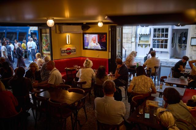 People watch on TV Pope Leo XIV presiding the Solemn Vespers at Notre-Dame Cathedral, in a bar in Paris on September 25, 2026 as part of his four days visit to France. (Photo by Kiran RIDLEY / AFP)