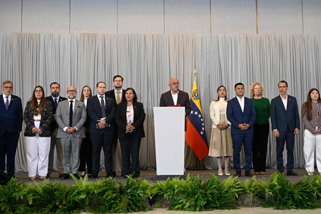 Venezuela's National Assembly President Jorge Rodriguez (C, right) and opposition delegation head Dinorah Figuera (C, left), accompanied by members of their respective delegations, deliver a joint statement following the signing of an agreement at the closing of the second round of political dialogue talks at the Melia hotel in Caracas on September 25, 2026. (Photo by Federico PARRA / AFP)