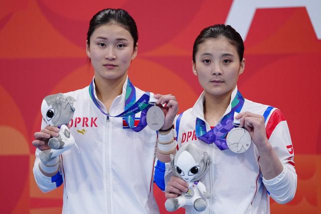 North Korea's Jo Jin Mi and Kim Mi Rae pose with their silver medals on the podium during the victory ceremony for the women's synchronised 10m platform final diving event during the 2026 Asian Games at the Tokyo Aquatics Centre in Tokyo on September 26, 2026. (Photo by Yuichi YAMAZAKI / AFP)