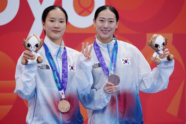 South Korea's Kim Na-hyun and Moon Na-yun pose with their bronze medals on the podium during the victory ceremony for the women's synchronised 10m platform final diving event during the 2026 Asian Games at the Tokyo Aquatics Centre in Tokyo on September 26, 2026. (Photo by Yuichi YAMAZAKI / AFP)