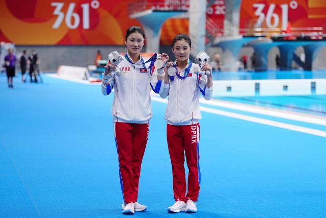 North Korea's Jo Jin Mi and Kim Mi Rae pose with their silver medals following the victory ceremony for the women's synchronised 10m platform final diving event during the 2026 Asian Games at the Tokyo Aquatics Centre in Tokyo on September 26, 2026. (Photo by Yuichi YAMAZAKI / AFP)