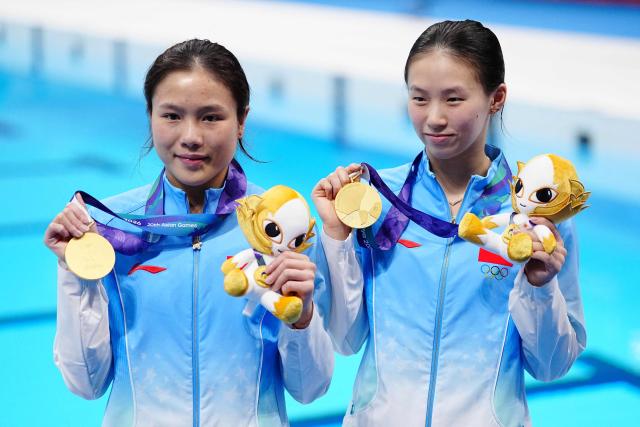 China's Chen Yuxi and Lu Wei pose with their gold medals following the victory ceremony for the women's synchronised 10m platform final diving event during the 2026 Asian Games at the Tokyo Aquatics Centre in Tokyo on September 26, 2026. (Photo by Yuichi YAMAZAKI / AFP)
