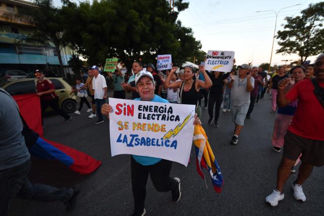 A demonstrator holds a sign calling for improvements to electricity services during a march demanding the return of Venezuelan opposition leader María Corina Machado to Venezuela, in Valencia, Venezuela, on September 25, 2026. (Photo by Jacinto OLIVEROS / AFP)