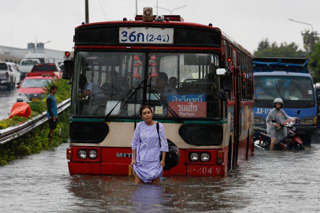 A woman walks through flood waters in front of a bus after heavy rain in Bangkok on September 26, 2026. Bangkok authorities declared a flood disaster across the Thai capital on September 26 after almost 48 hours of heavy rain left canals full, roads submerged and residents knee-deep in water. (Photo by Sarot Meksophawannakul / THAI NEWS PIX / AFP)