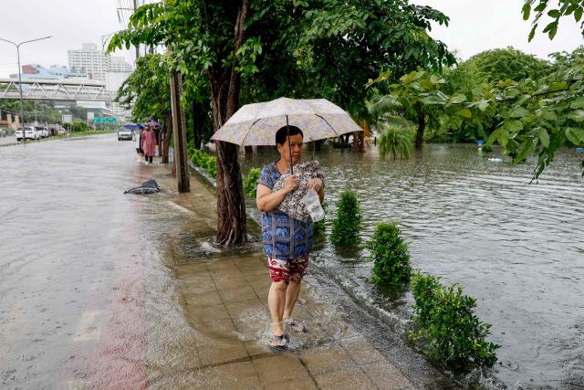 A woman walk through flood waters after heavy rain in Bangkok on September 26, 2026. Bangkok authorities declared a flood disaster across the Thai capital on September 26 after almost 48 hours of heavy rain left canals full, roads submerged and residents knee-deep in water. (Photo by Sarot Meksophawannakul / THAI NEWS PIX / AFP)