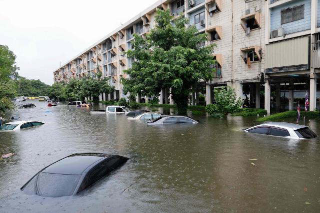 Flood waters submerge cars next to residential buildings after heavy rain in Bangkok on September 26, 2026. Bangkok authorities declared a flood disaster across the Thai capital on September 26 after almost 48 hours of heavy rain left canals full, roads submerged and residents knee-deep in water. (Photo by Sarot Meksophawannakul / THAI NEWS PIX / AFP)