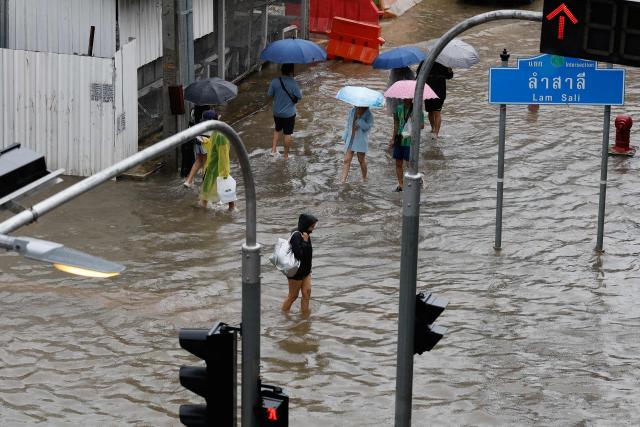 People walk through flood waters after heavy rain in Bangkok on September 26, 2026. Bangkok authorities declared a flood disaster across the Thai capital on September 26 after almost 48 hours of heavy rain left canals full, roads submerged and residents knee-deep in water. (Photo by Sarot Meksophawannakul / THAI NEWS PIX / AFP)