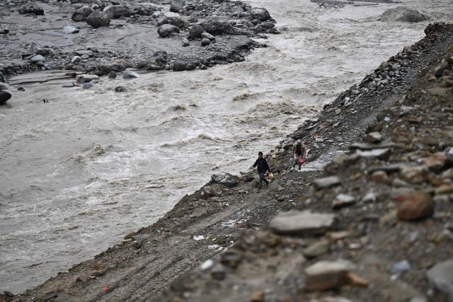 People walk along a washed-out highway in the aftermath of the August 26 flash flood at Betrawoti Bazaar in Nepal's Nuwakot district on September 26, 2026. The August 26 flood, triggered by a glacial mountain collapse near the China-Nepal border, has killed more than 1,400 people, the majority in Nepal. Over 5,000 remain missing in Nepal since the tsunami-like waves swept away roads, bridges and settlements in the mountainous regions up north, and battered crucial hydropower projects. (Photo by PRAKASH MATHEMA / AFP)