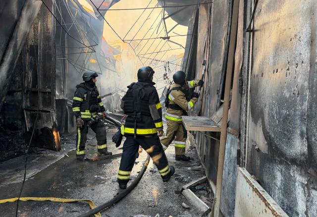 Ukrainian firefighters work to extinguish a fire at a local market following a Russian drone strike in Zaporizhzhia on September 26, 2026, amid the Russian invasion of Ukraine. (Photo by Darya NAZAROVA / AFP)